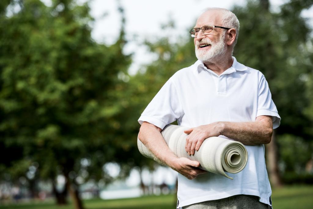 hombre mayor feliz con alfombra de fitness en el parque
 - Foto, Imagen