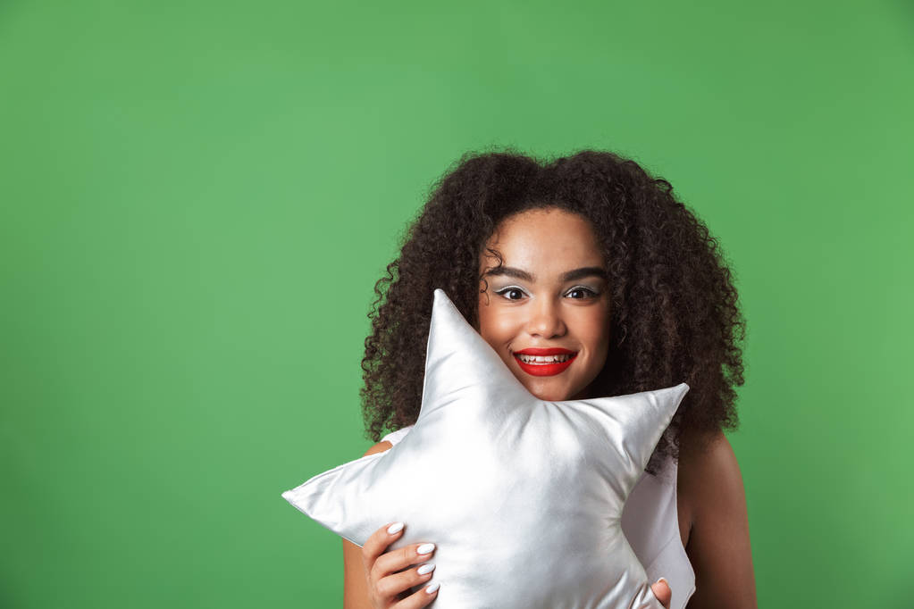 Cheerful young african woman wearing dress standing isolated, holding star shaped pillow - Photo, Image