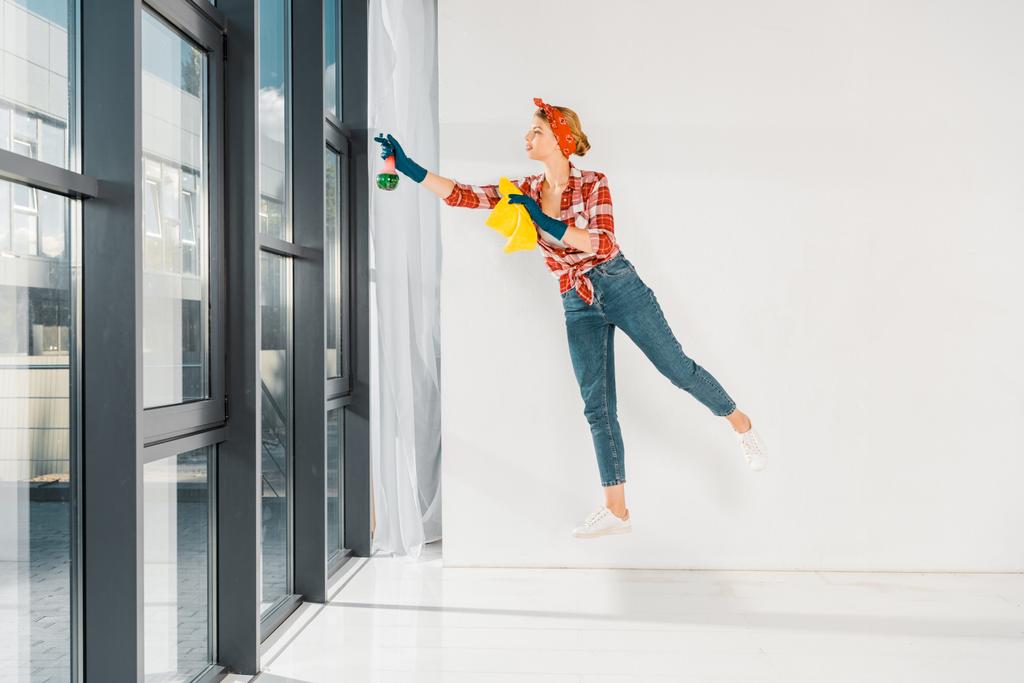 fille flottante en jeans et chemise à carreaux nettoyage des fenêtres avec chiffon et pulvérisation
  - Photo, image