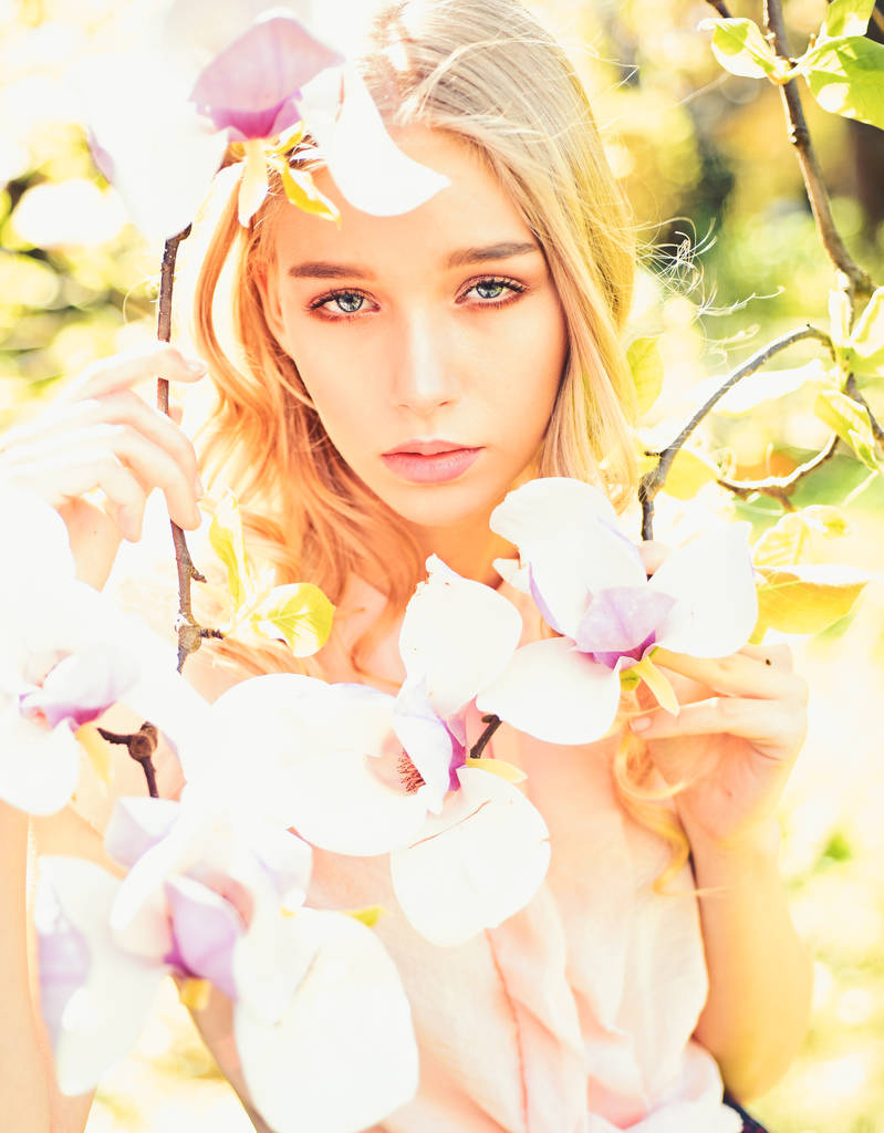 Fille sur le visage rêveur, blonde tendre près de fleurs de magnolia, fond nature. Les jeunes femmes aiment les fleurs dans le jardin. Concept de fleur de printemps. Dame marche dans le parc le jour ensoleillé du printemps
. - Photo, image