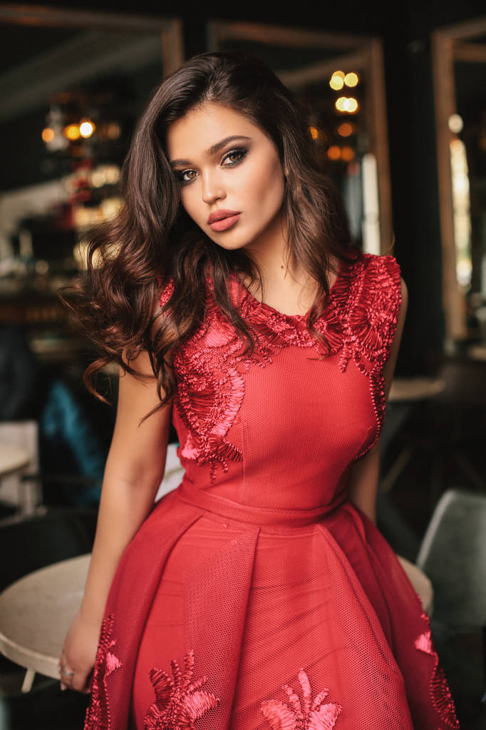エレガントな赤いドレスで暗い巻き毛の美しい若いセクシーな女性のファッション インテリア写真 - 写真・画像