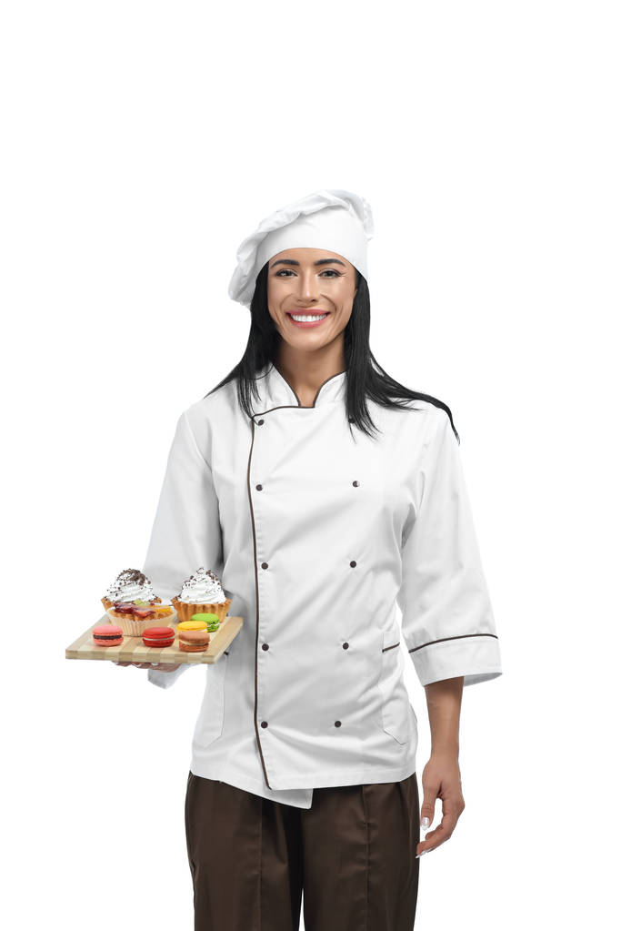 Young confectioner in uniform holding tray with sweets. - Photo, Image