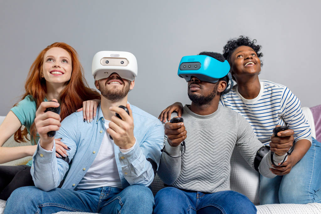 Dos chicos jugando videojuegos usando gafas VR y novias los apoyan
. - Foto, imagen