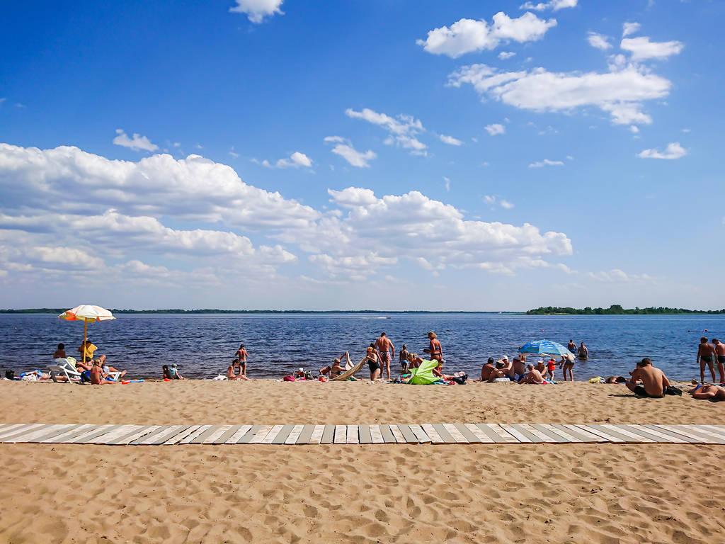 Saratov / Russia - July 4, 2018: People sunbathe on the sandy beach and swim in the river. On a Sunny summer day. - Photo, Image