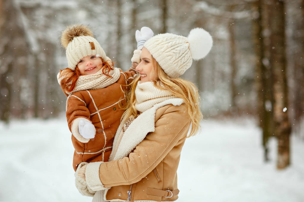 Malá zrzavá dívka dítě a matka se baví v parku v zimě, sněží - Fotografie, Obrázek