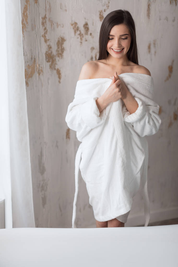 mooie jonge dame in bad badjas gaan naar een bad te nemen in witte badkamer - Foto, afbeelding