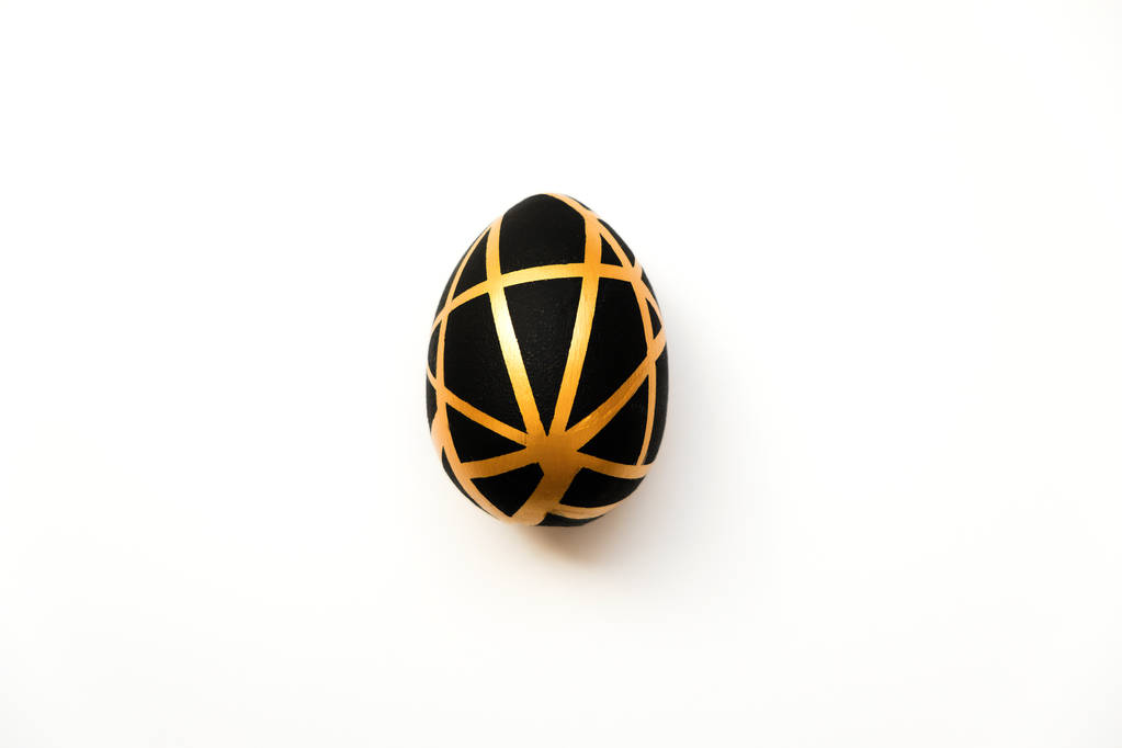 Huevo dorado de Pascua con patrón negro geométrico aislado sobre fondo blanco. Mínimo concepto de Pascua. Vista superior, plano
 - Foto, Imagen