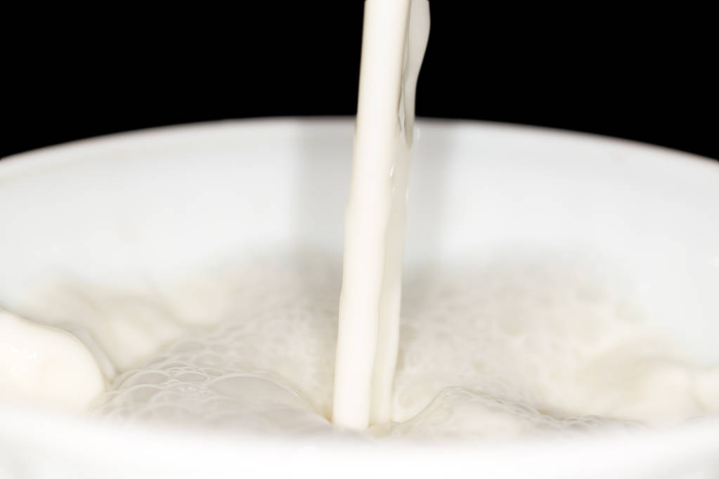 брызги молока на черном фоне - Фото, изображение