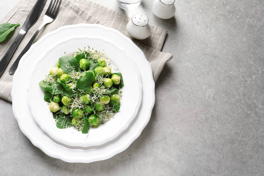 Plate of delicious salad with Brussels sprouts on grey table, top view. Space for text - Photo, Image