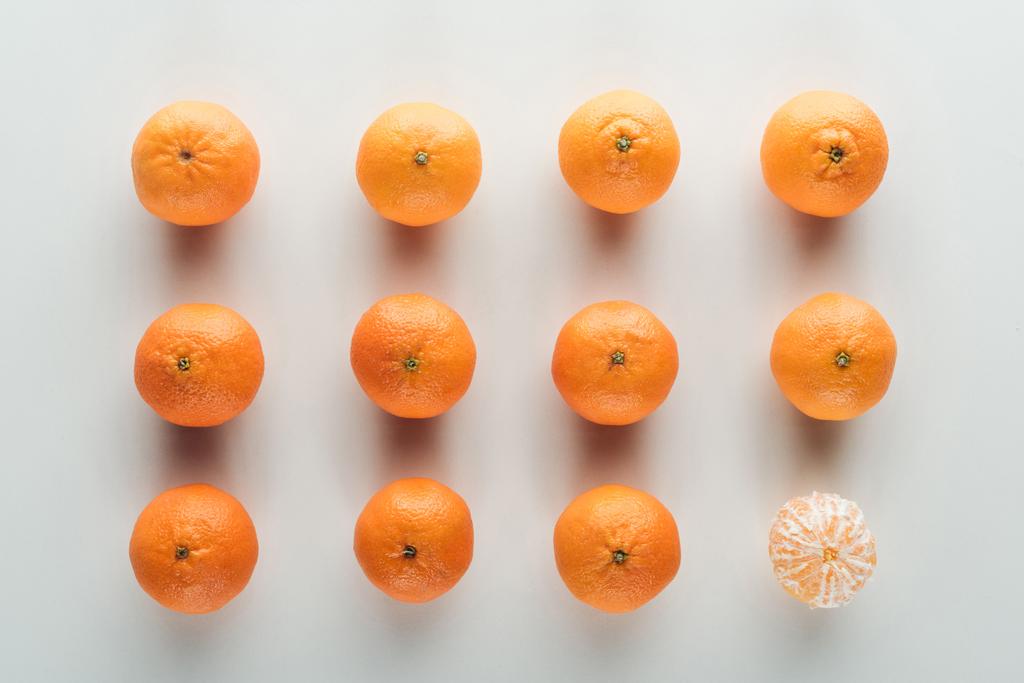 flat lay com tangerinas não descascadas e um descascado no fundo branco
 - Foto, Imagem