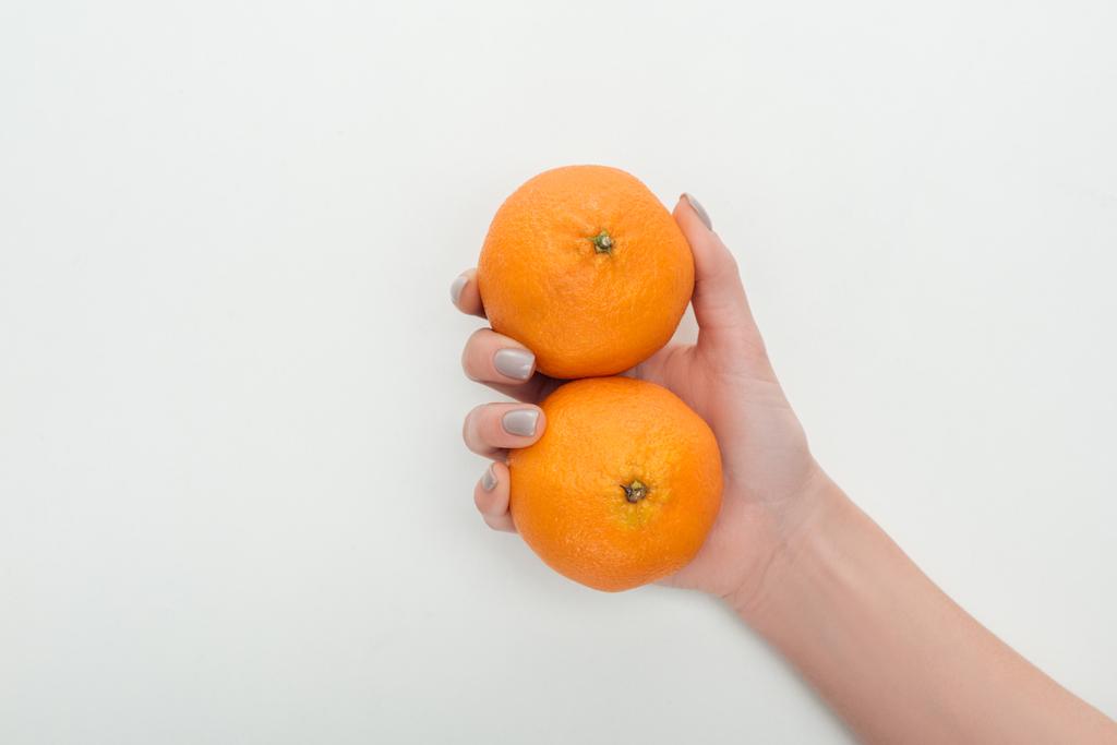 bijgesneden beeld van vrouw met twee hele mandarijnen in hand op witte achtergrond - Foto, afbeelding