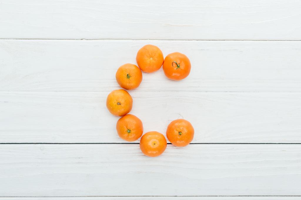 pohled shora písmene c z čerstvé mandarinky na dřevěné bílé pozadí - Fotografie, Obrázek
