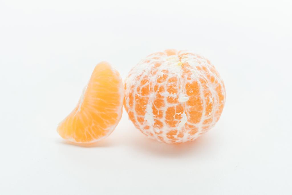 mandarina pelada entera naranja jugosa madura con rebanada sobre fondo blanco
 - Foto, Imagen