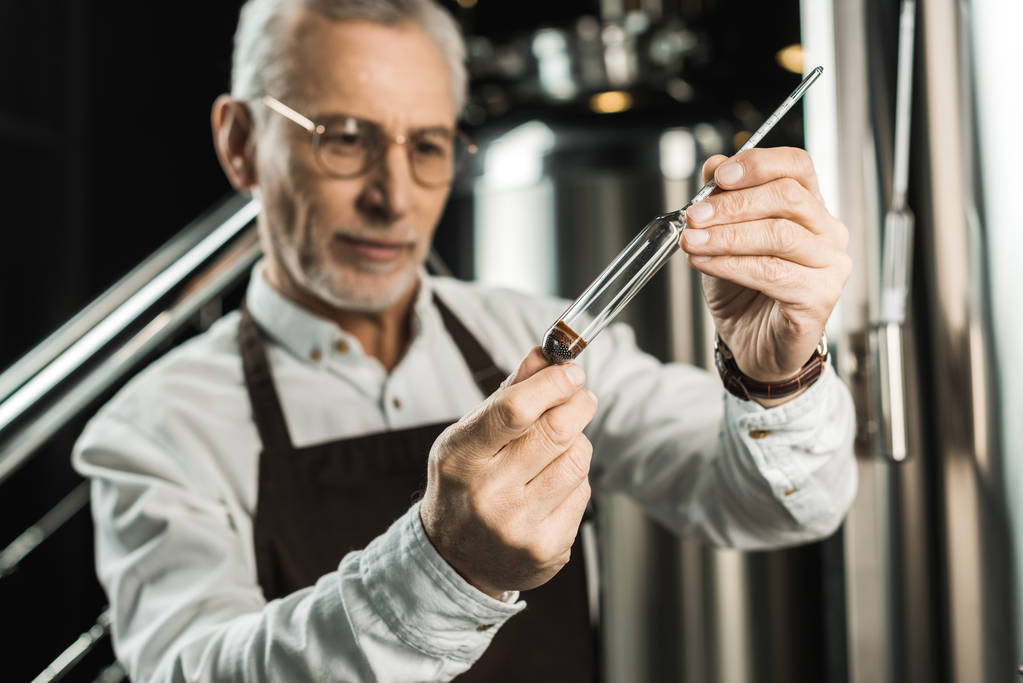 szelektív összpontosít a férfi brewer vizsgálja mérőlombikban sörgyár sör - Fotó, kép