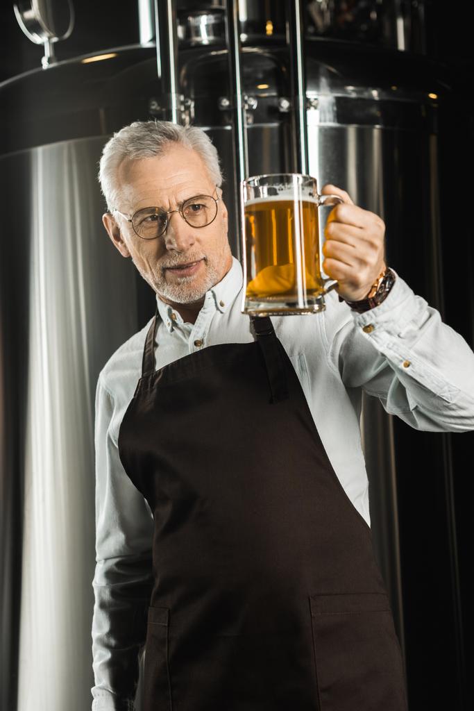 професійний пивовар, дивлячись на келих пива в пивоварні
 - Фото, зображення