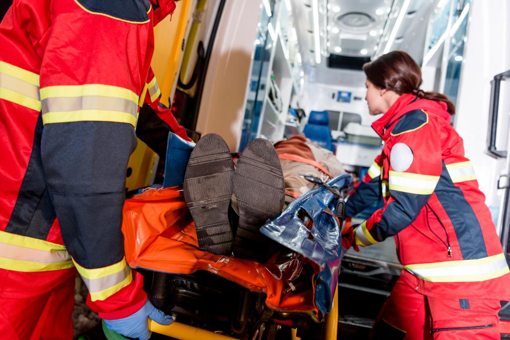 Paramedici transportating patiënt op gurney in ambulance auto - Foto, afbeelding