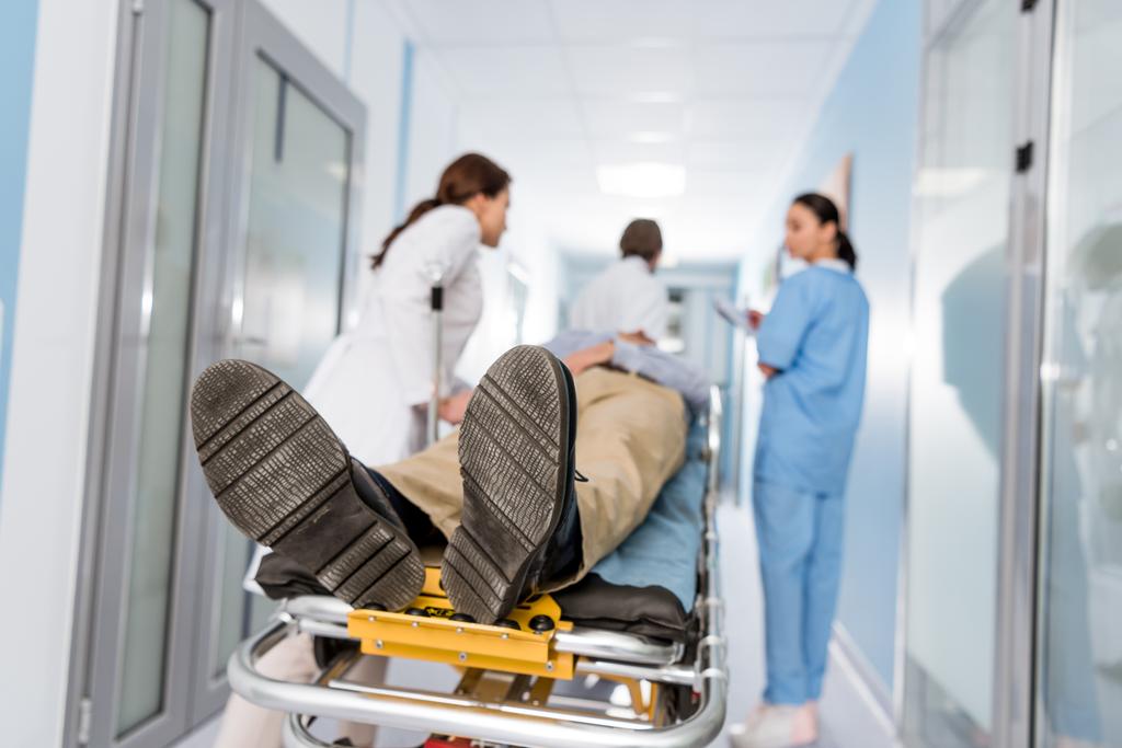 Artsen vervoer patiënt op gurney voor operatiekamer - Foto, afbeelding