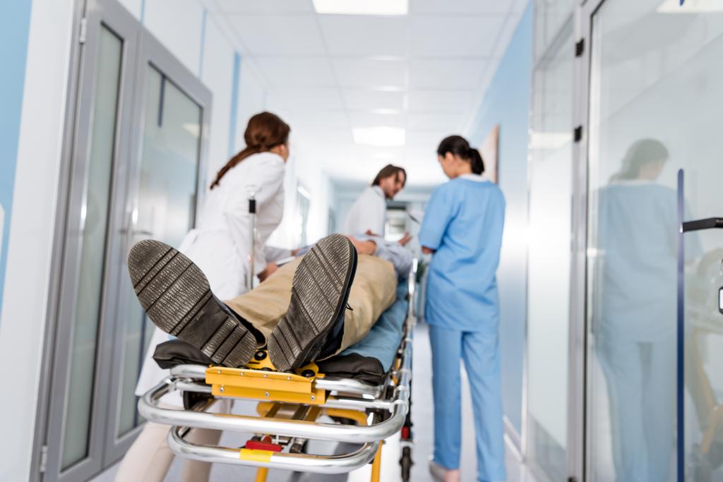 Lääkärit univormussa kuljettavat potilaan leikkaussaliin
 - Valokuva, kuva