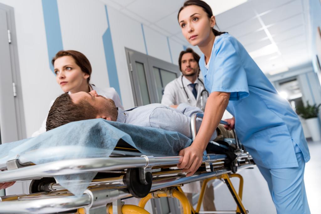 Лікарі та медсестра перевозять несвідомого пацієнта на Ґурні
 - Фото, зображення