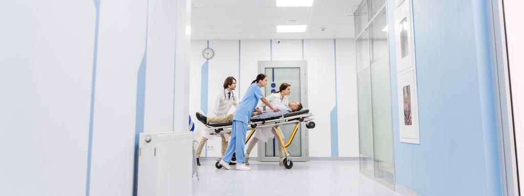 Medici concentrati e infermiere che trasportano pazienti incoscienti su barelle
  - Foto, immagini