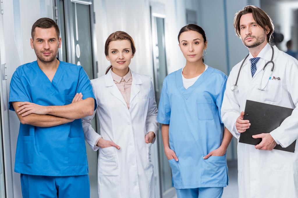 Врачи и медсестры в синей форме смотрят в камеру
 - Фото, изображение