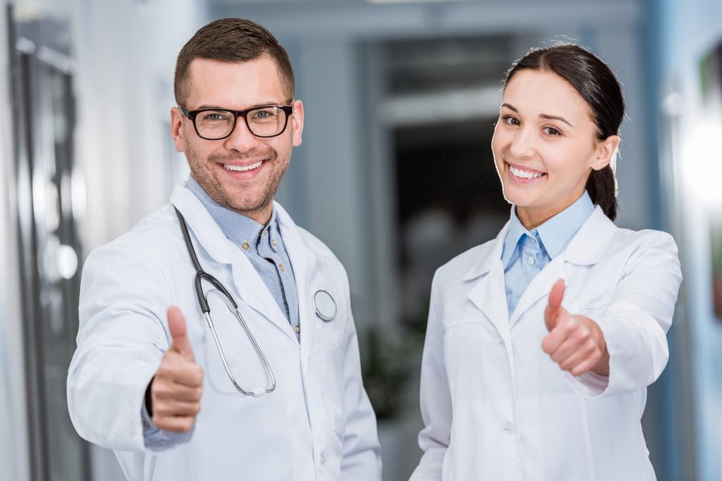 Γελώντας τους γιατρούς σε λευκό παλτό δείχνει τους αντίχειρες επάνω - Φωτογραφία, εικόνα