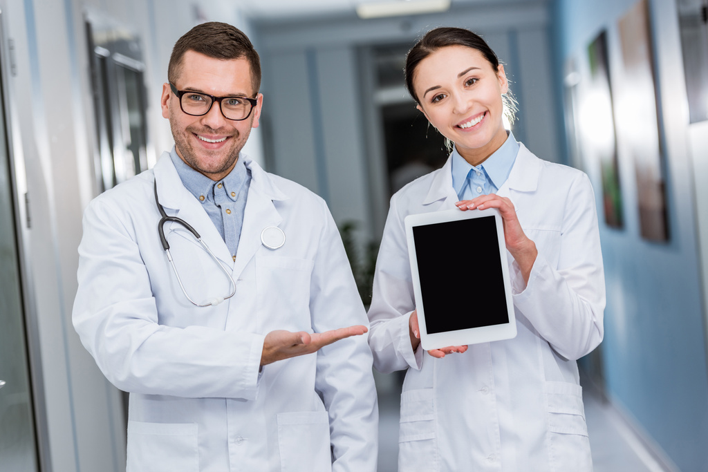 Gülümseyen doktorlar dijital tablet ile boş perde holding - Fotoğraf, Görsel