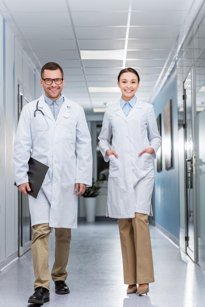 Gelukkig artsen in witte jassen wandelen down hall samen - Foto, afbeelding
