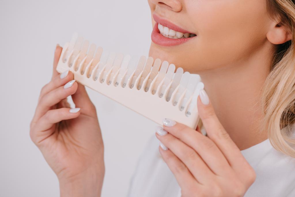 vista parziale della donna sorridente che tiene i denti tavolozza dei colori isolata sul bianco, concetto di sbiancamento dei denti
 - Foto, immagini