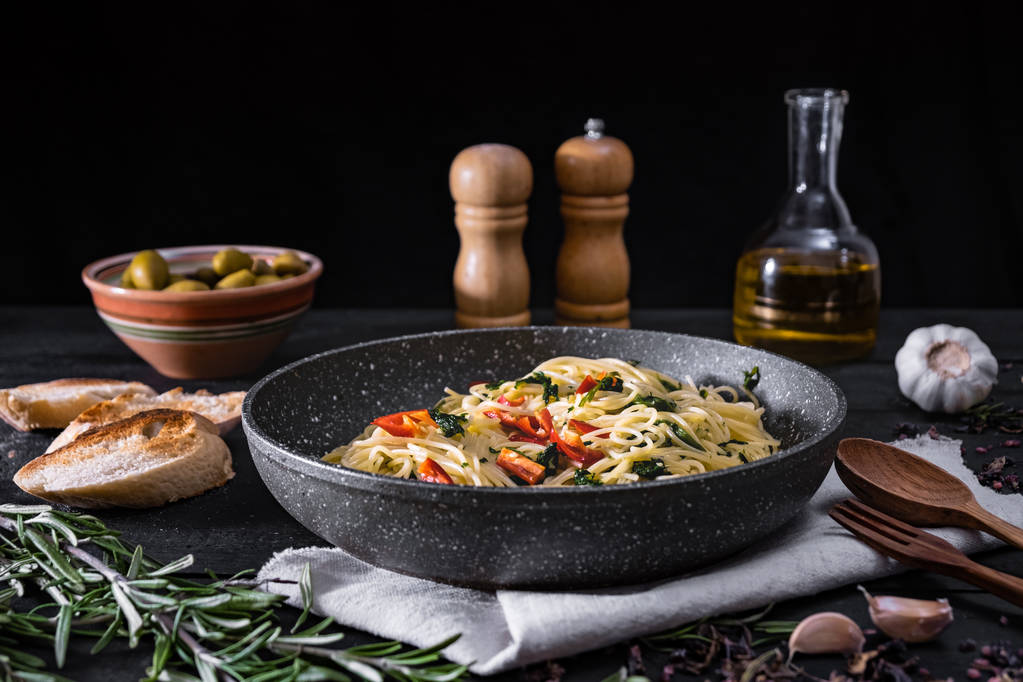 Pan keitettyä italialaista pastaa. Perinteinen spagetti ateria vihanneksia ja oliiveja mustalla maalaismainen tausta
 - Valokuva, kuva