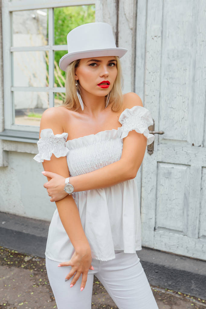 Sexy sposa moderna in cappello cilindro bianco in piedi accanto alla vecchia porta d'epoca bianca e finestra a specchio
. - Foto, immagini