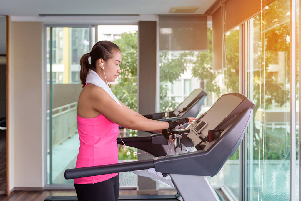 fitness girl exercising on a cardio machine and Listening to music for relaxation in morning - Photo, Image