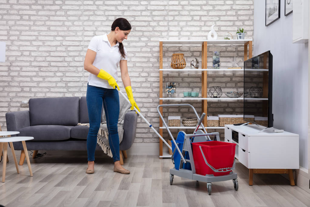 Conserje femenina piso de limpieza con fregona en la sala de estar
 - Foto, Imagen