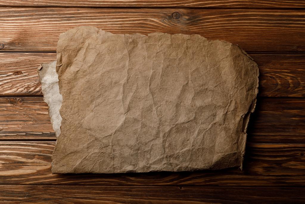 Brown leeftijd perkament blad liggend op houten achtergrond - Foto, afbeelding