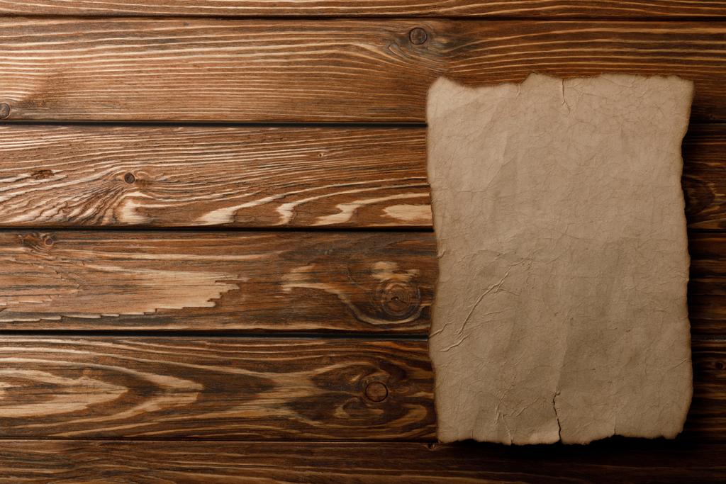 bovenaanzicht van leeftijd papier blad liggend op houten achtergrond - Foto, afbeelding