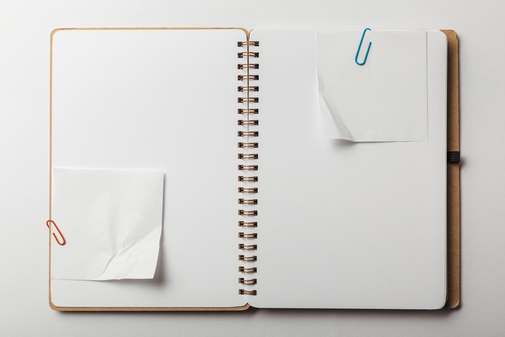 вид зверху відкритого ноутбука з липкими нотатками та паперовими затискачами на білому тлі
 - Фото, зображення