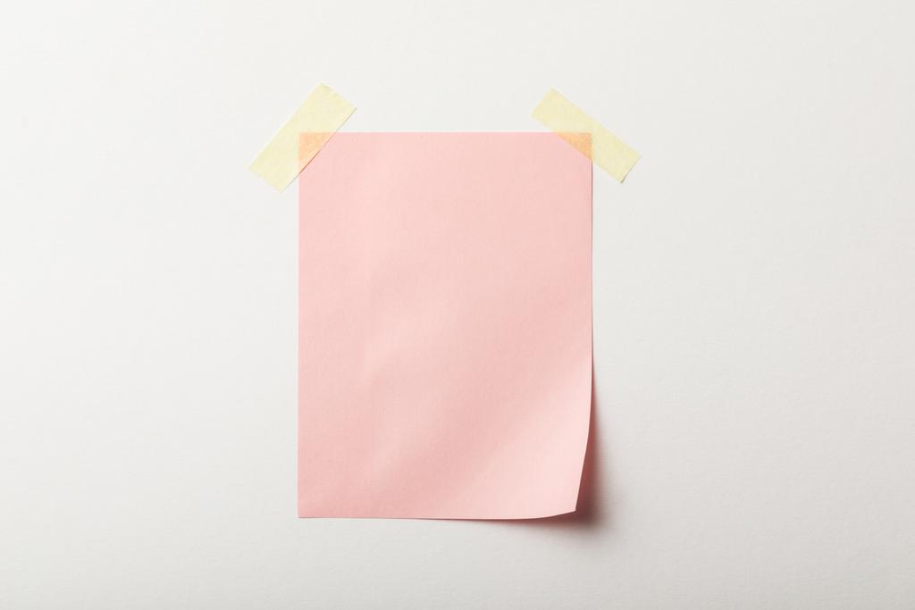 vaaleanpunainen tyhjä paperi, jossa teippi valkoisella pohjalla
 - Valokuva, kuva