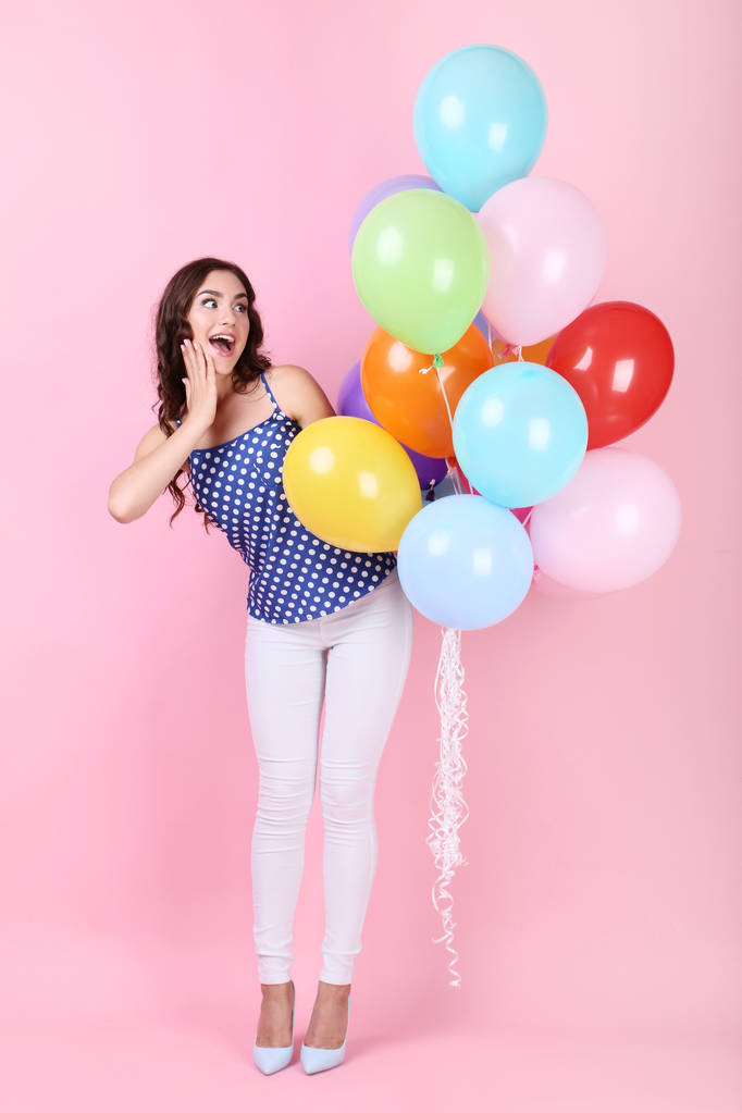 glückliches Mädchen mit bunten Luftballons auf rosa Hintergrund - Foto, Bild