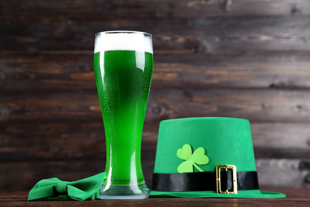 St. Patrick's Day. Pohár zöld sör a csokornyakkendő és a kalap, a fából készült háttér - Fotó, kép