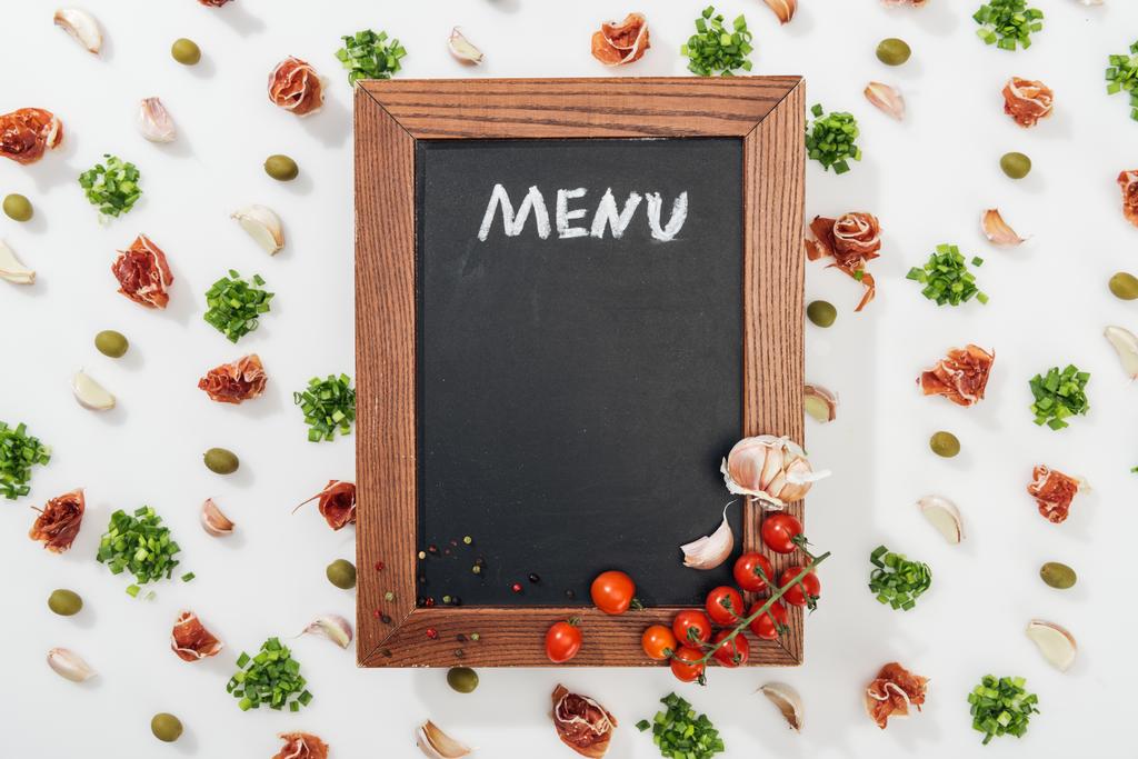 vista dall'alto della lavagna di gesso con menù lettering tra prosciutto, olive, spicchi d'aglio, verde e pomodorini
 - Foto, immagini