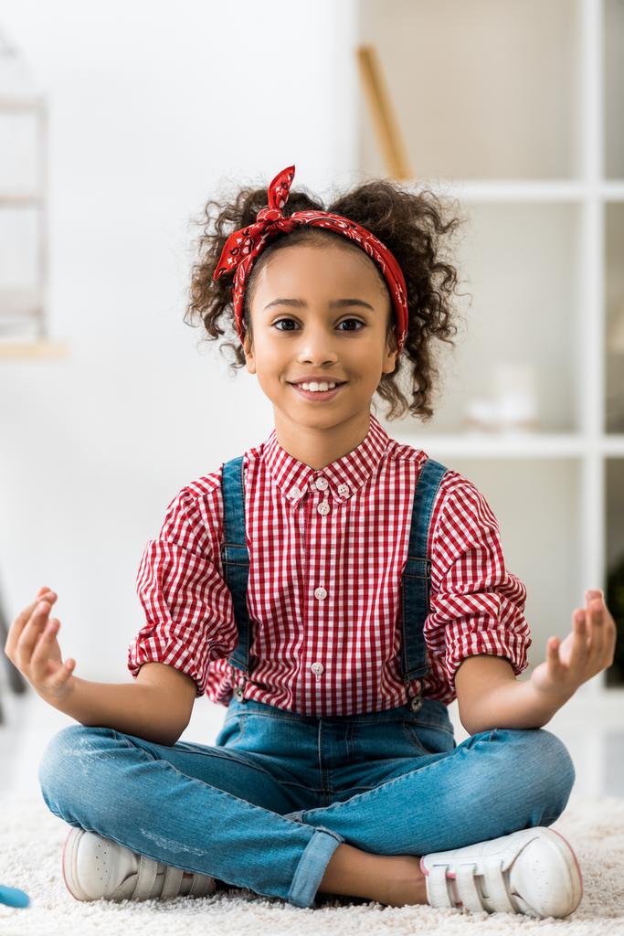 smiling african american child sitting in lotus pose and looking at camera - Photo, Image