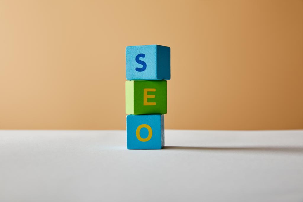 vertical seo lettering made of multicolored blocks on white table and beige background - Photo, Image