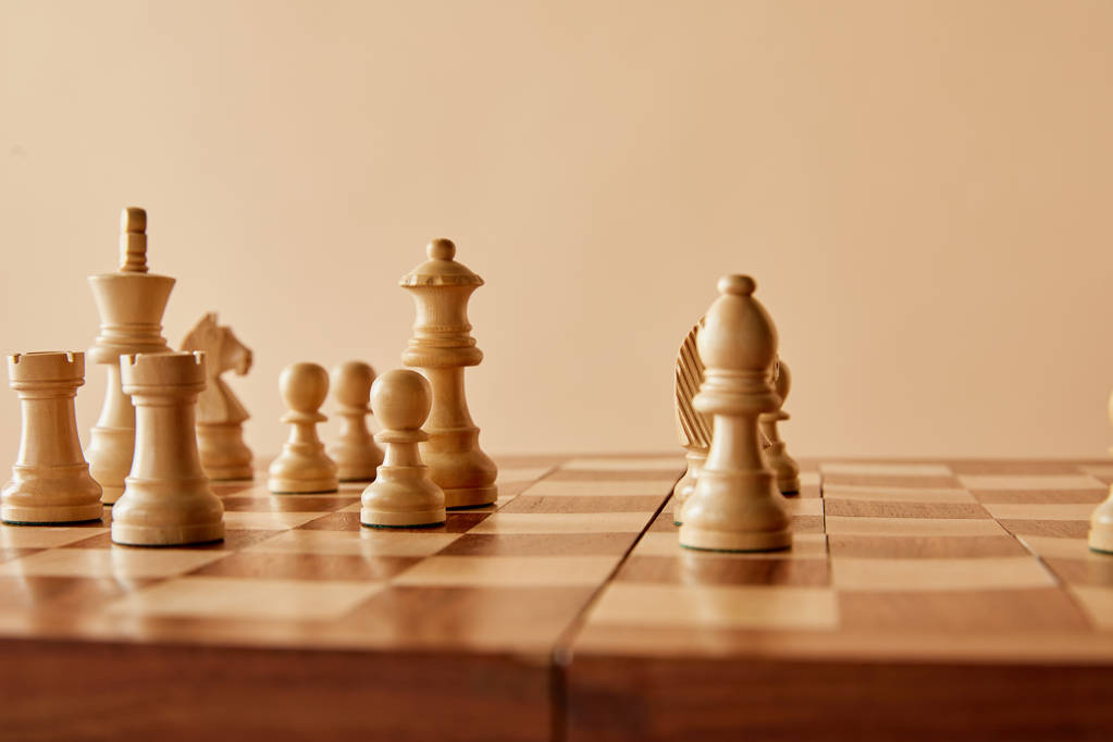 Schaken op de houten schaak bestuur en beige achtergrond - Foto, afbeelding