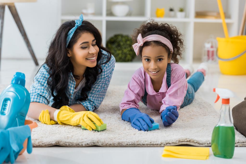 felice afro americano mamma e bambino pulizia tappeto con spugne
 - Foto, immagini