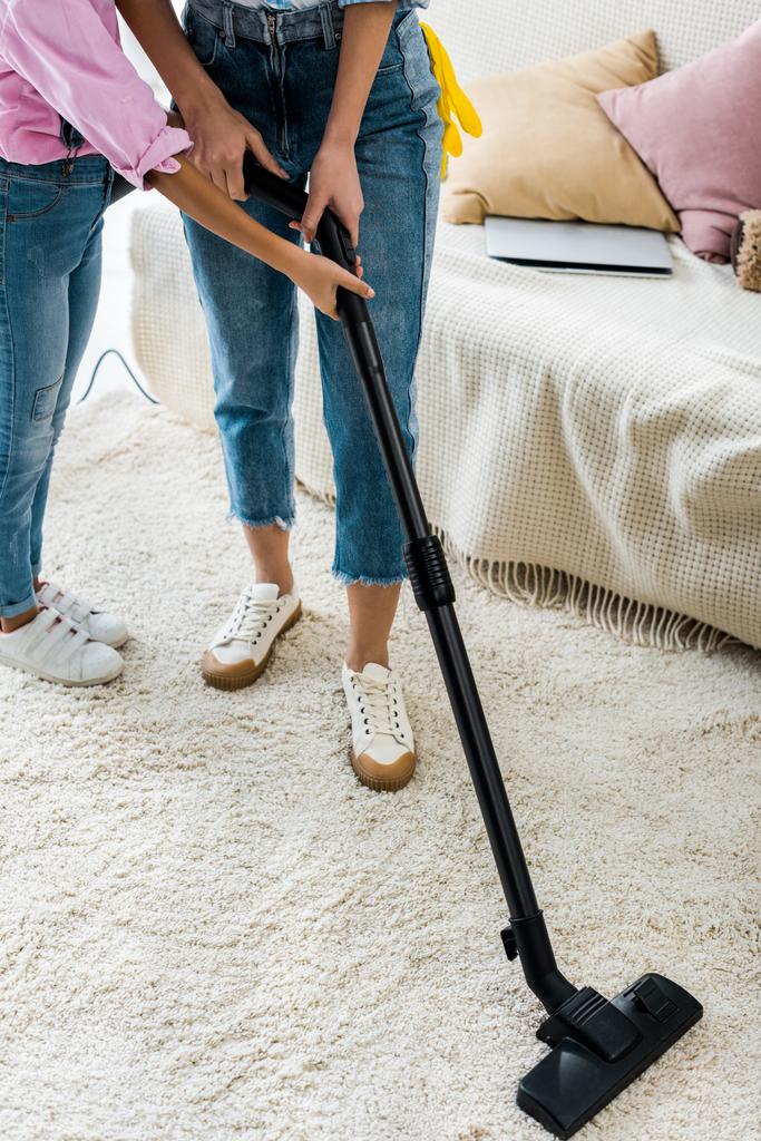 cropped view of african american child helping mother vacuuming carpet - Photo, Image