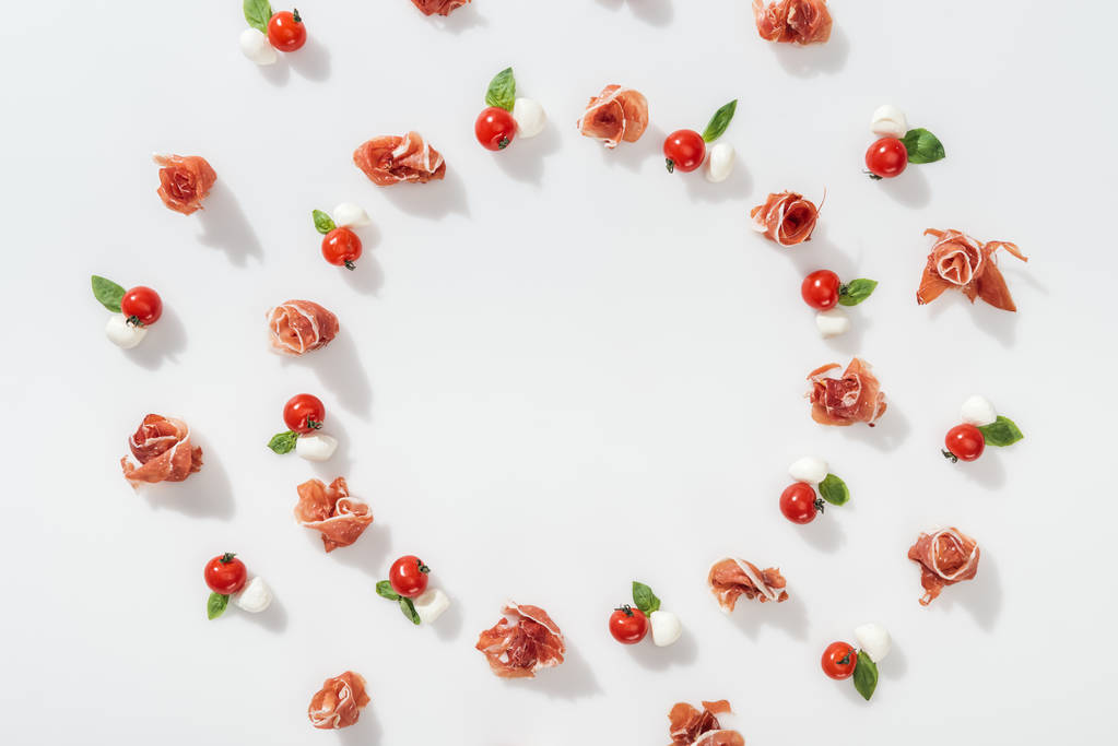 mieszkanie świeckich smaczny szynki w pobliżu czerwone pomidory cherry, mozzarella sera i zielonej bazylii liści na białym tle - Zdjęcie, obraz
