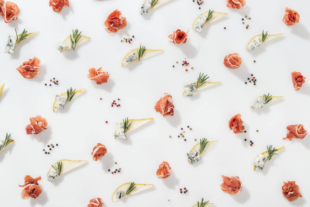 flat lay of delicious prosciutto near sliced pears with blue cheese and rosemary twigs on white background - Photo, Image