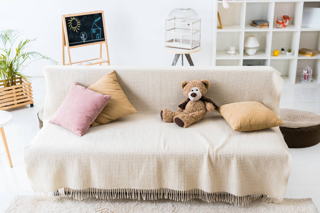 枕とテディベアの居心地の良いリビング ルームは、快適なソファの上組み立てください。  - 写真・画像