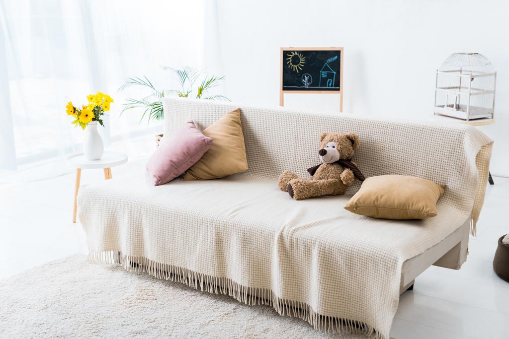 φως, ευρύχωρο δωμάτιο με άνετο καναπέ με μαξιλάρια και αρκουδάκι  - Φωτογραφία, εικόνα