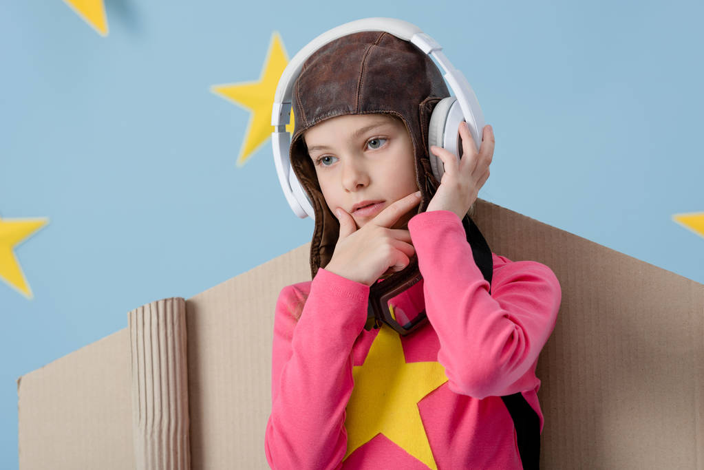 Zamyšlený dítě v letu helmu poslech hudby na modré hvězdné pozadí - Fotografie, Obrázek